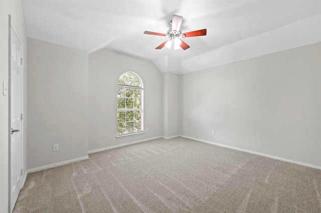 empty room featuring ceiling fan, vaulted ceiling, and carpet