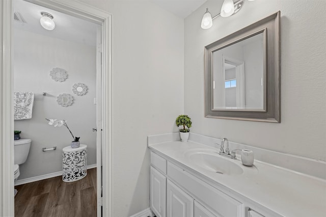 bathroom with toilet, vanity, and hardwood / wood-style flooring