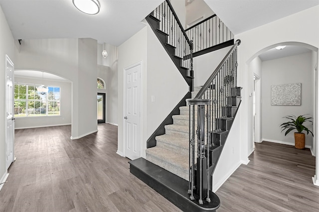 stairway with wood-type flooring and a notable chandelier