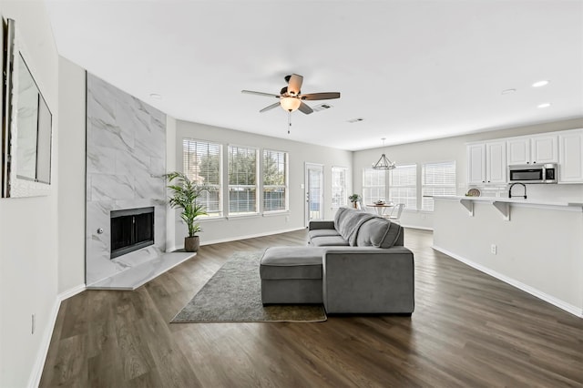 living room featuring ceiling fan, dark hardwood / wood-style floors, a high end fireplace, and sink