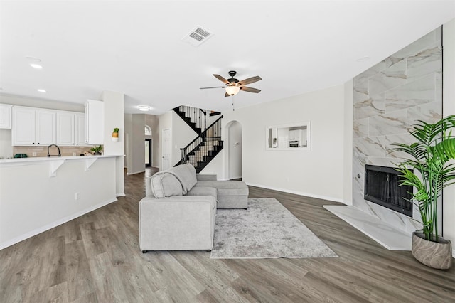 living room with ceiling fan, wood-type flooring, and a high end fireplace