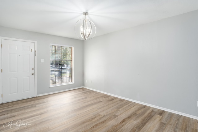 empty room with a chandelier and light wood-type flooring