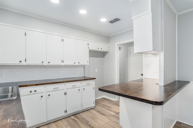 kitchen with light hardwood / wood-style flooring, ornamental molding, decorative backsplash, and white cabinetry