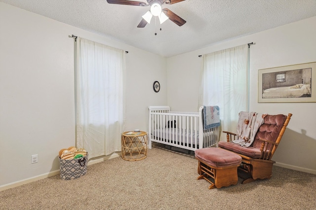 carpeted bedroom featuring a crib, a textured ceiling, and ceiling fan