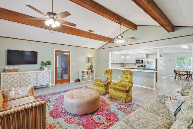 living room with wood walls, vaulted ceiling with beams, light hardwood / wood-style floors, and ceiling fan