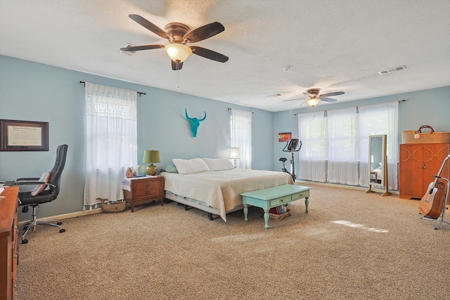 bedroom with ceiling fan, carpet floors, and a textured ceiling