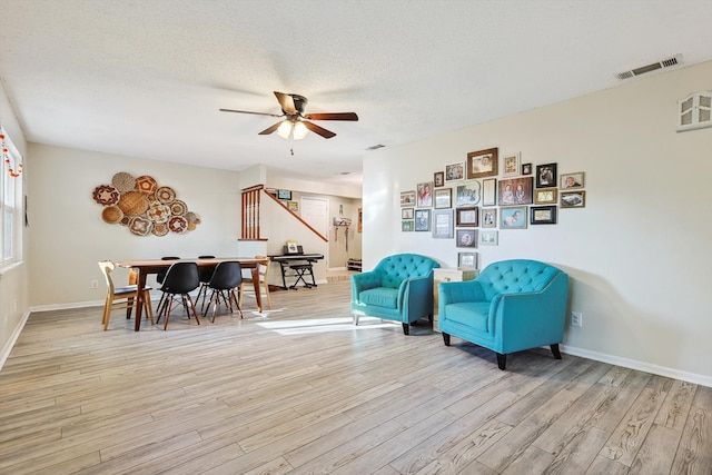 sitting room with a textured ceiling, light wood-type flooring, and ceiling fan