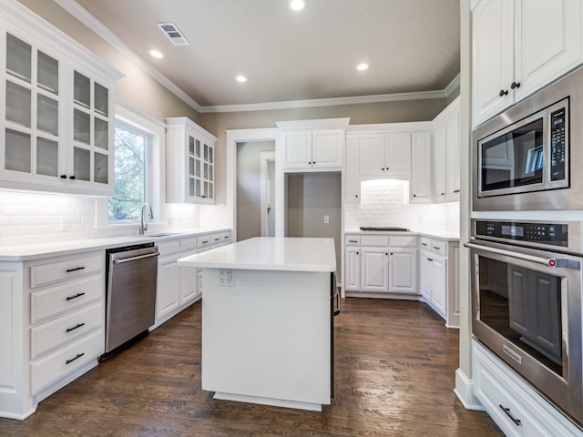 kitchen with a kitchen island, appliances with stainless steel finishes, dark hardwood / wood-style floors, and white cabinetry