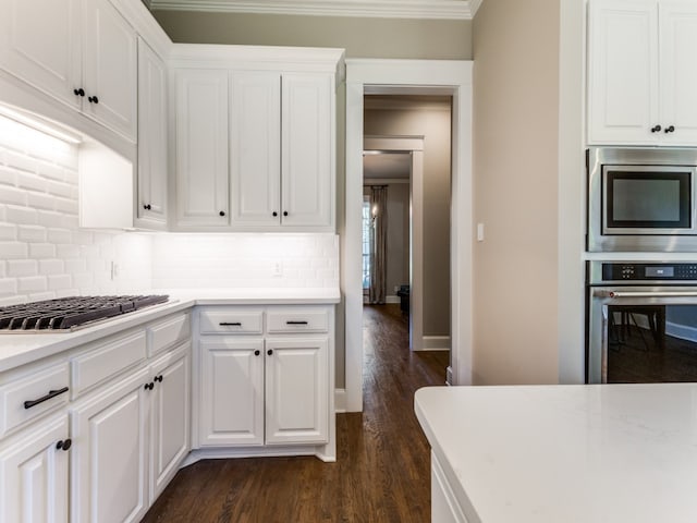 kitchen featuring decorative backsplash, stainless steel appliances, dark hardwood / wood-style floors, white cabinets, and ornamental molding