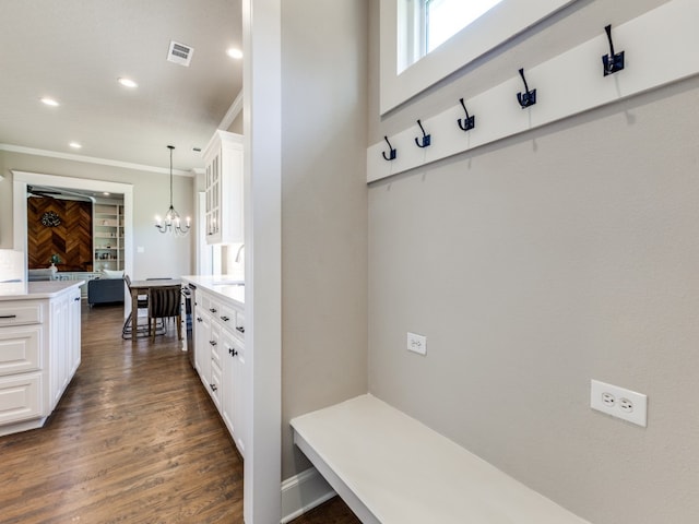 mudroom with an inviting chandelier, crown molding, and dark wood-type flooring