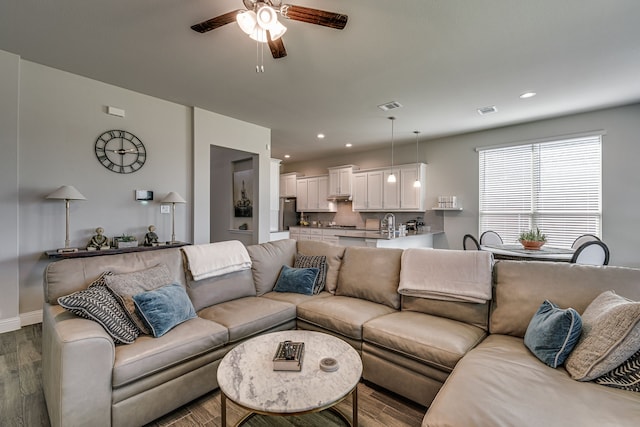 living room featuring ceiling fan and dark wood-type flooring