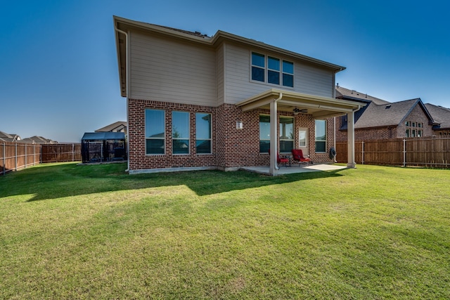 rear view of house with ceiling fan, a yard, and a patio