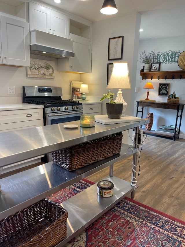 kitchen featuring stainless steel counters, hardwood / wood-style floors, stainless steel gas range, and white cabinetry