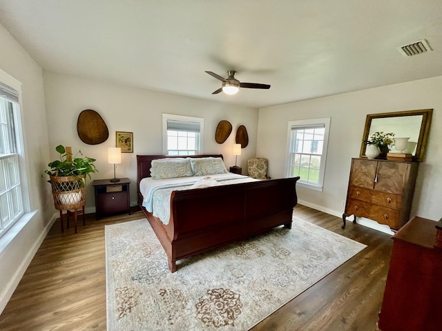 bedroom with dark hardwood / wood-style floors, multiple windows, and ceiling fan