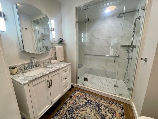 bathroom featuring an enclosed shower, vanity, and wood-type flooring