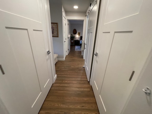 hallway with a barn door and dark hardwood / wood-style floors