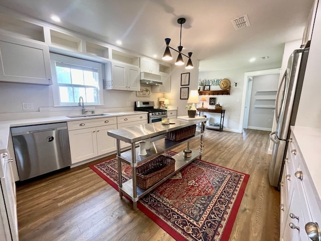 kitchen with appliances with stainless steel finishes, hanging light fixtures, white cabinetry, and sink