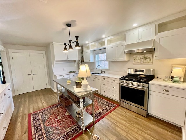 kitchen featuring light hardwood / wood-style flooring, gas range, decorative light fixtures, and white cabinetry