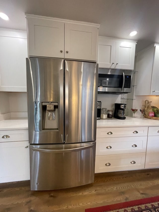 kitchen featuring stainless steel appliances, dark hardwood / wood-style floors, and white cabinetry