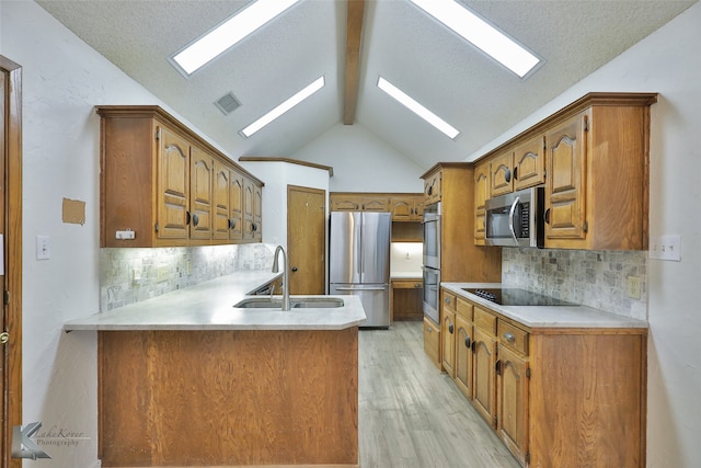 kitchen featuring stainless steel appliances, lofted ceiling, kitchen peninsula, sink, and light wood-type flooring