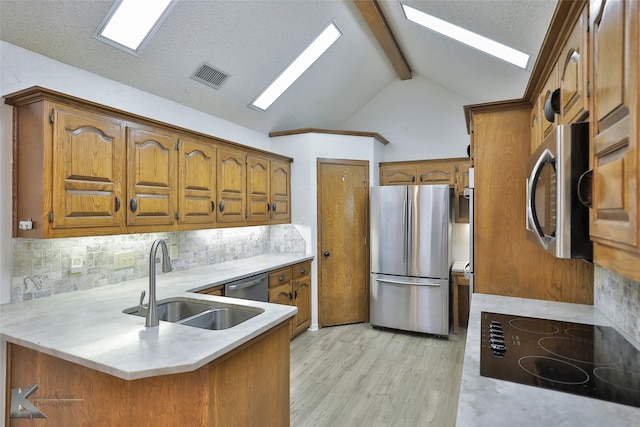 kitchen featuring light hardwood / wood-style floors, kitchen peninsula, decorative backsplash, sink, and appliances with stainless steel finishes