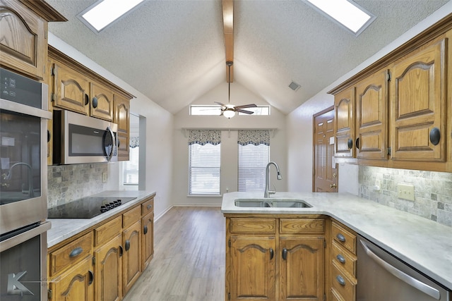 kitchen featuring light wood-type flooring, stainless steel appliances, sink, and backsplash