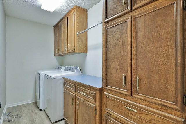 laundry area with cabinets, separate washer and dryer, a textured ceiling, and light hardwood / wood-style flooring