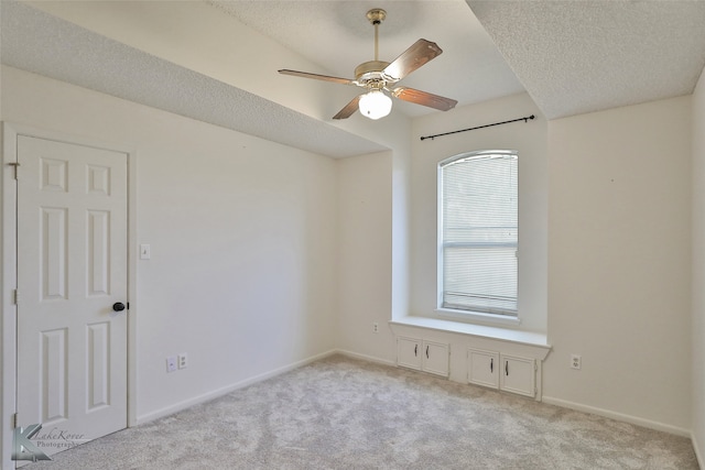 carpeted empty room with ceiling fan and a textured ceiling