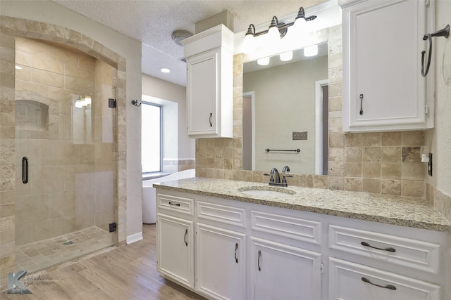 bathroom with walk in shower, vanity, a textured ceiling, ornate columns, and hardwood / wood-style flooring