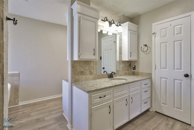 bathroom with backsplash, hardwood / wood-style floors, and a textured ceiling