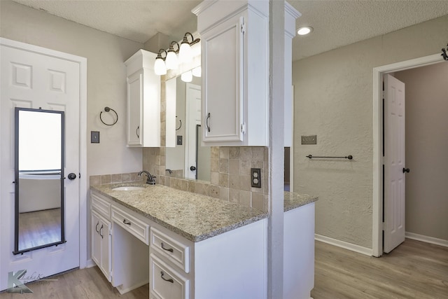 bathroom with hardwood / wood-style floors, a textured ceiling, vanity, and tasteful backsplash