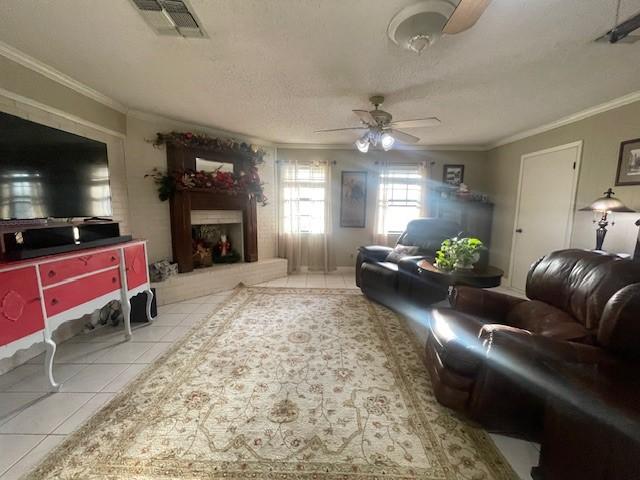 tiled living room with ceiling fan, ornamental molding, and a textured ceiling