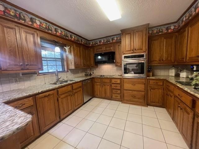 kitchen featuring backsplash, sink, light tile patterned floors, light stone countertops, and appliances with stainless steel finishes