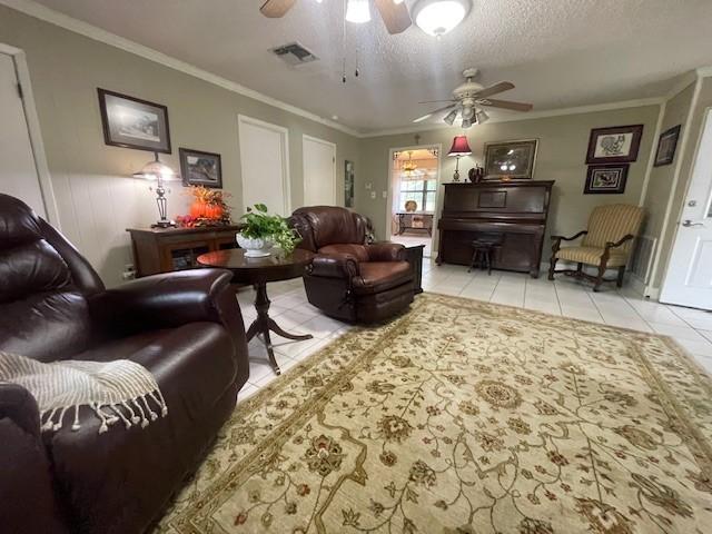 tiled living room featuring a textured ceiling, ceiling fan, and crown molding