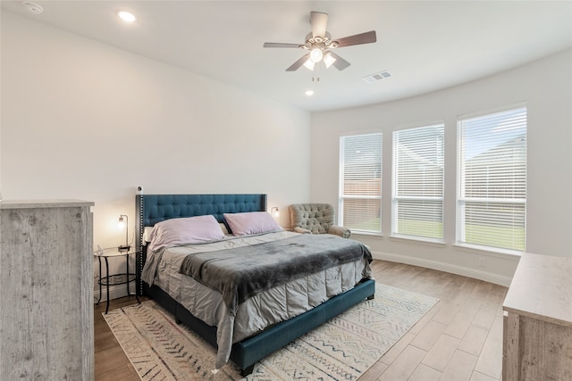 bedroom with multiple windows, ceiling fan, and light hardwood / wood-style floors