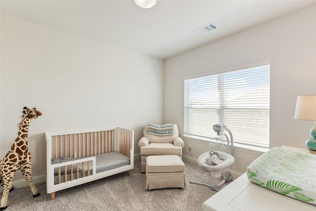 carpeted bedroom featuring a nursery area