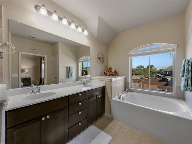 bathroom featuring a tub to relax in, vaulted ceiling, tile patterned flooring, and vanity