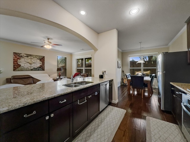 kitchen featuring dark wood-type flooring, decorative light fixtures, sink, dishwasher, and light stone countertops