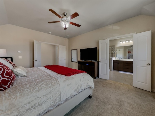 bedroom with lofted ceiling, ceiling fan, connected bathroom, and light carpet