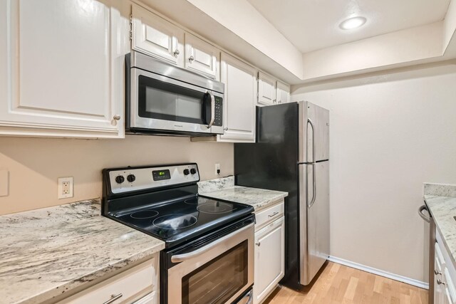 kitchen featuring light stone counters, sink, white cabinetry, light hardwood / wood-style flooring, and appliances with stainless steel finishes