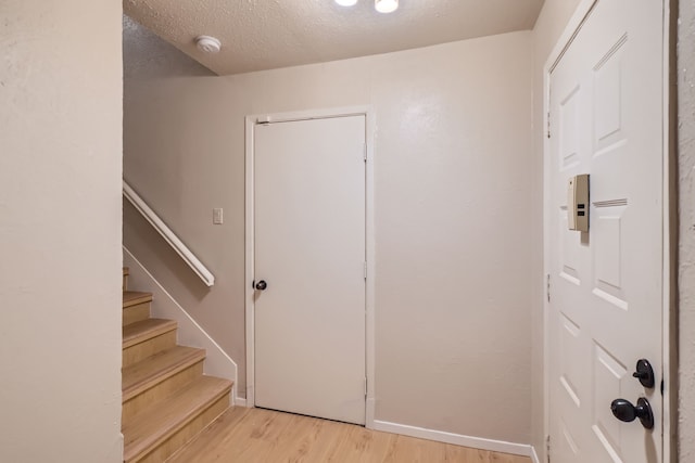 foyer with light wood-type flooring and a textured ceiling