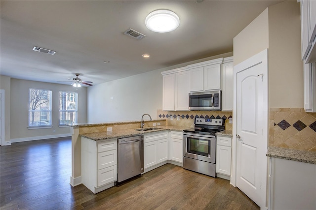 kitchen featuring kitchen peninsula, white cabinets, appliances with stainless steel finishes, and dark hardwood / wood-style flooring