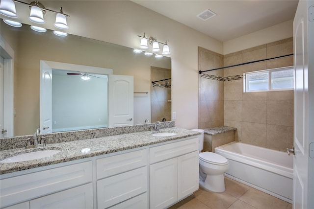 full bathroom featuring ceiling fan, tiled shower / bath, vanity, tile patterned floors, and toilet