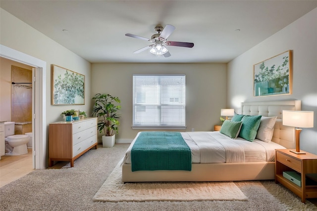 carpeted bedroom with ensuite bathroom and ceiling fan