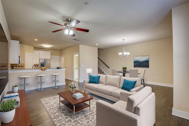 living room featuring ceiling fan with notable chandelier and hardwood / wood-style floors