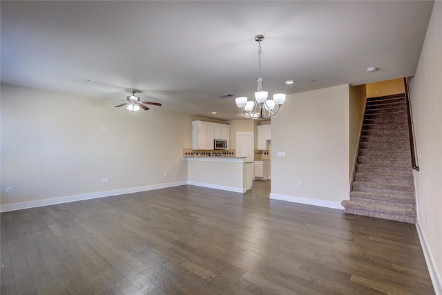 unfurnished living room featuring ceiling fan with notable chandelier and dark hardwood / wood-style floors