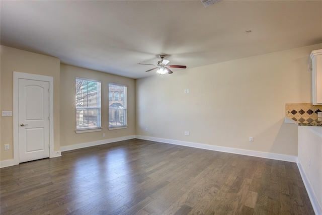 unfurnished living room featuring dark wood-type flooring and ceiling fan