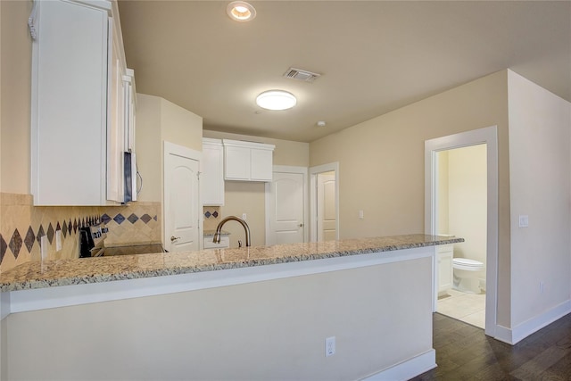 kitchen featuring range, dark wood-type flooring, light stone countertops, kitchen peninsula, and white cabinetry