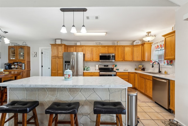 kitchen featuring appliances with stainless steel finishes, hanging light fixtures, sink, and a center island