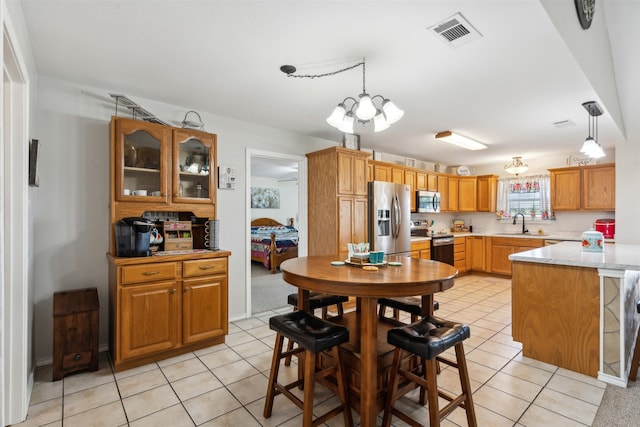 kitchen with a notable chandelier, decorative light fixtures, stainless steel appliances, and light stone countertops